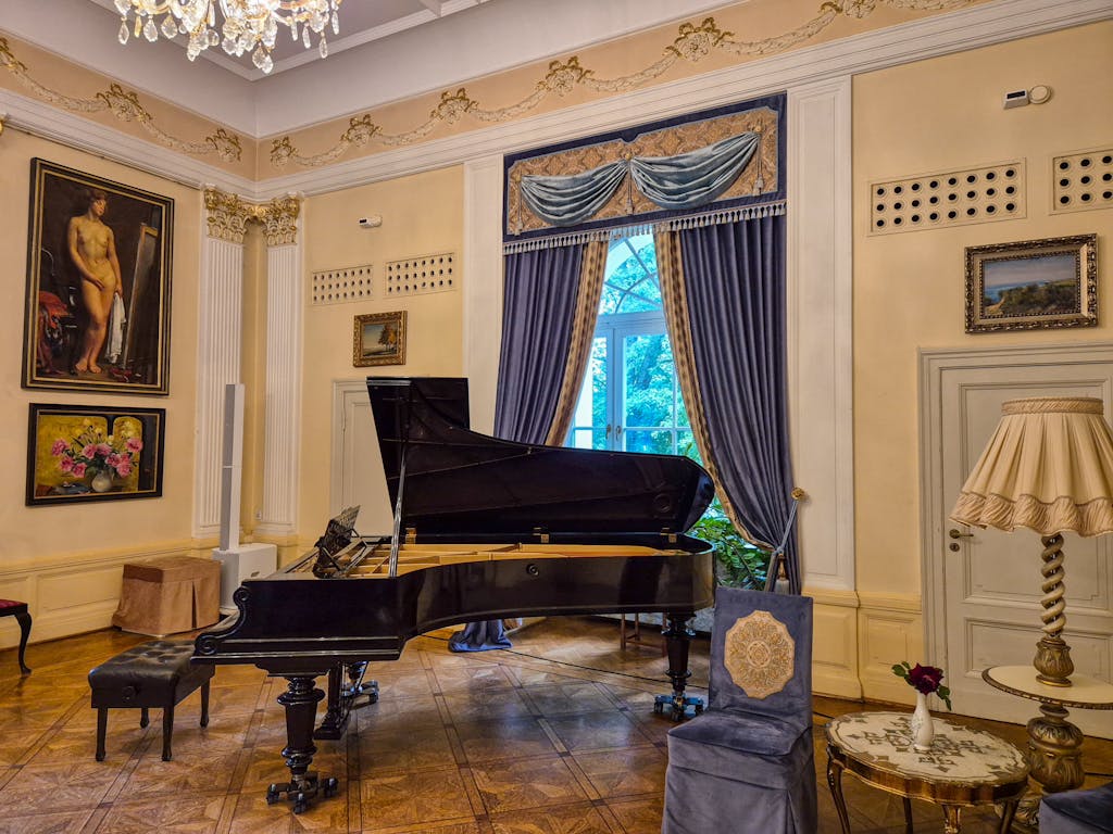 Luxurious interior with a grand piano, classic paintings, and chandeliers.