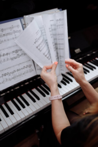 Hands holding sheet music at piano