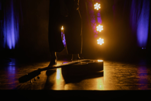 Red stage curtain with spotlight illuminating an empty performance stage