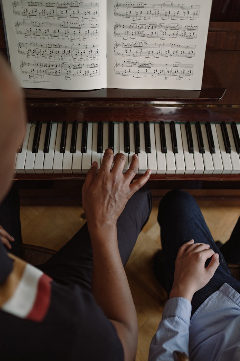 Hands on piano keys during an interactive lesson with music sheets.