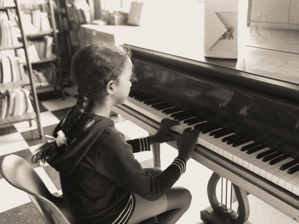 A young girl practices piano indoors in a cozy home setting, focused and serene.